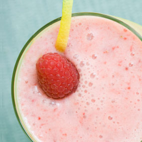 Pink raspberry smoothie with a fresh raspberry on top