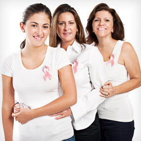 Three women of varying ages wear pink ribbons. 