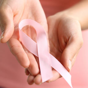 A woman holds a pink ribbon in her hands. 