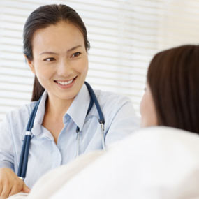 A doctor has a hopeful look as she talks with a female patient.