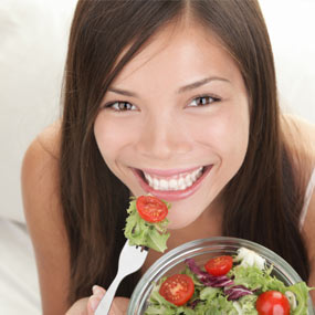 Happy girl eating salad.