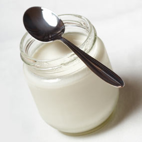 A jar of plain yogurt with a spoon.