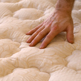 Hand testing how firm a mattress is.