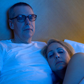 Man and woman watching tv in bed.