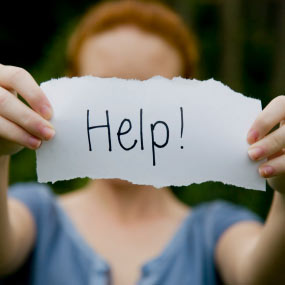 A woman holds a sign that says "help!"
