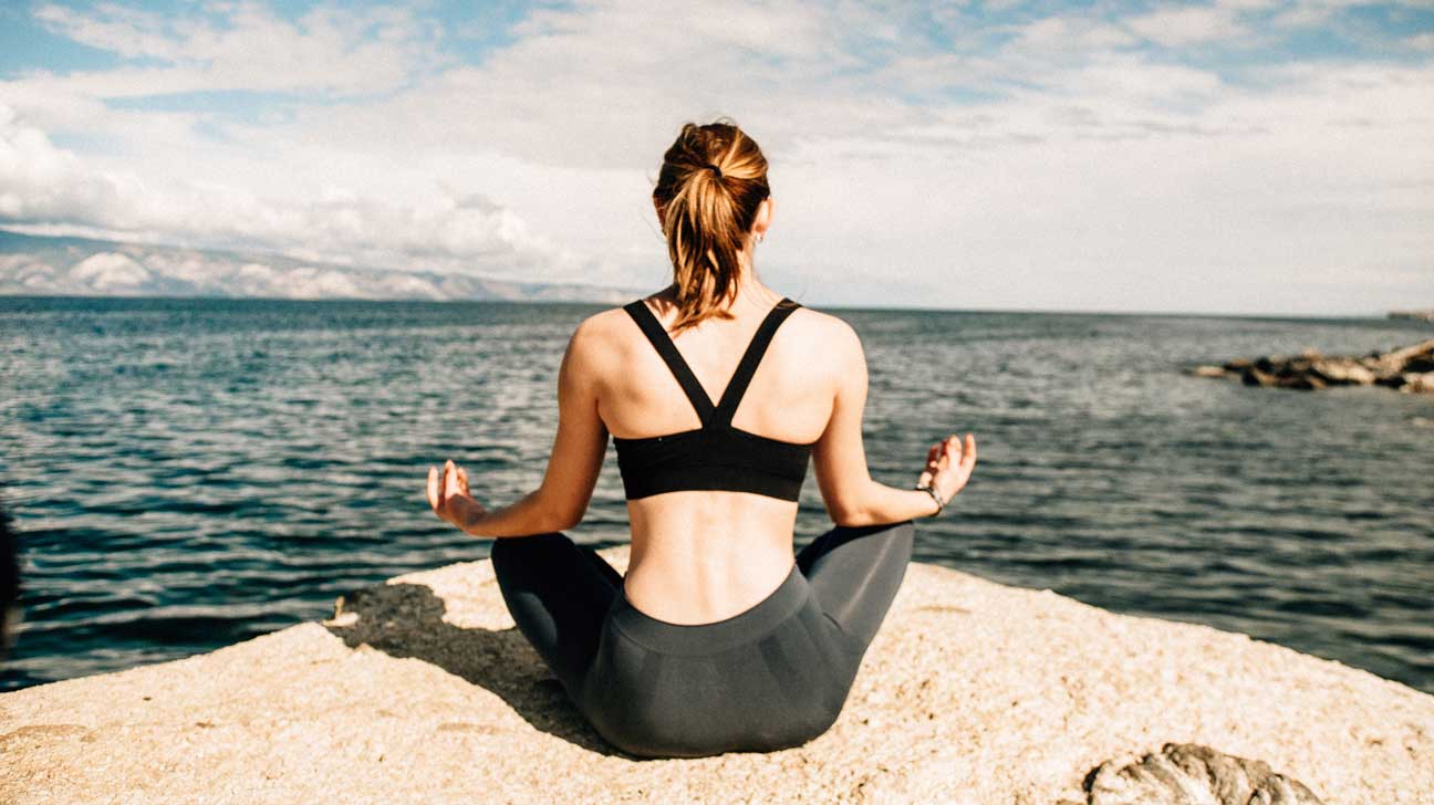 Woman Meditating By Ocean